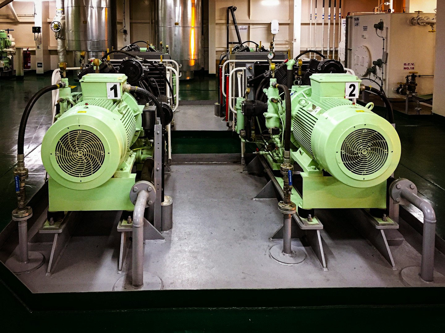 Two large green industrial motors on a metal platform.