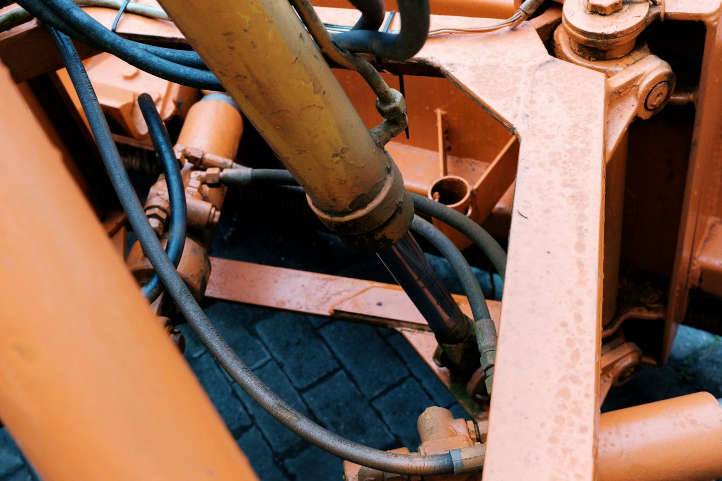 Orange hydraulic machinery with a central piston and thick hoses.